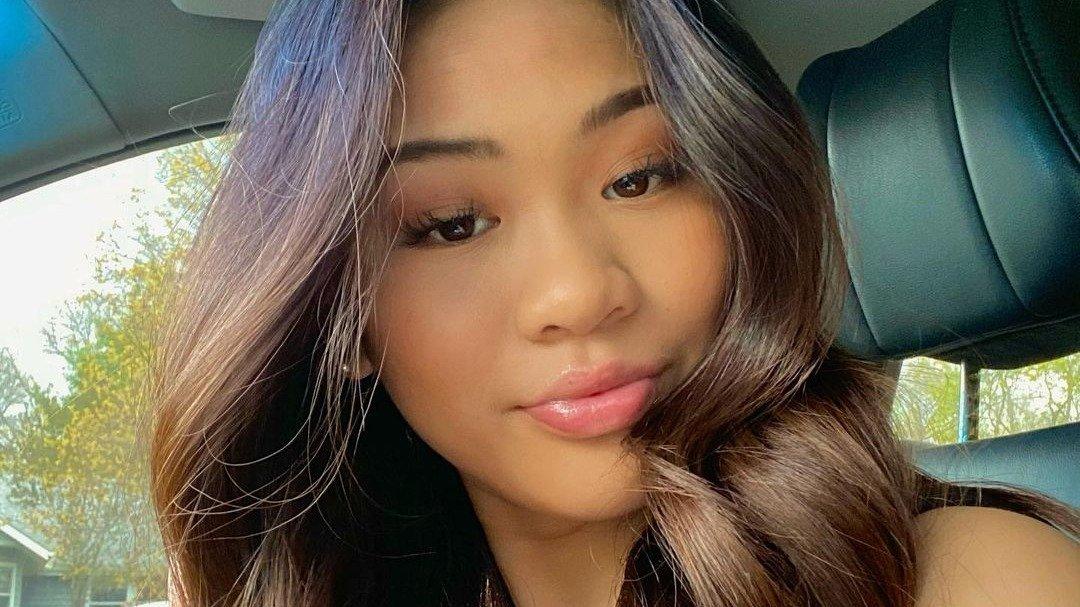 Suni Lee with wavy hair posing for a selfie in her car.