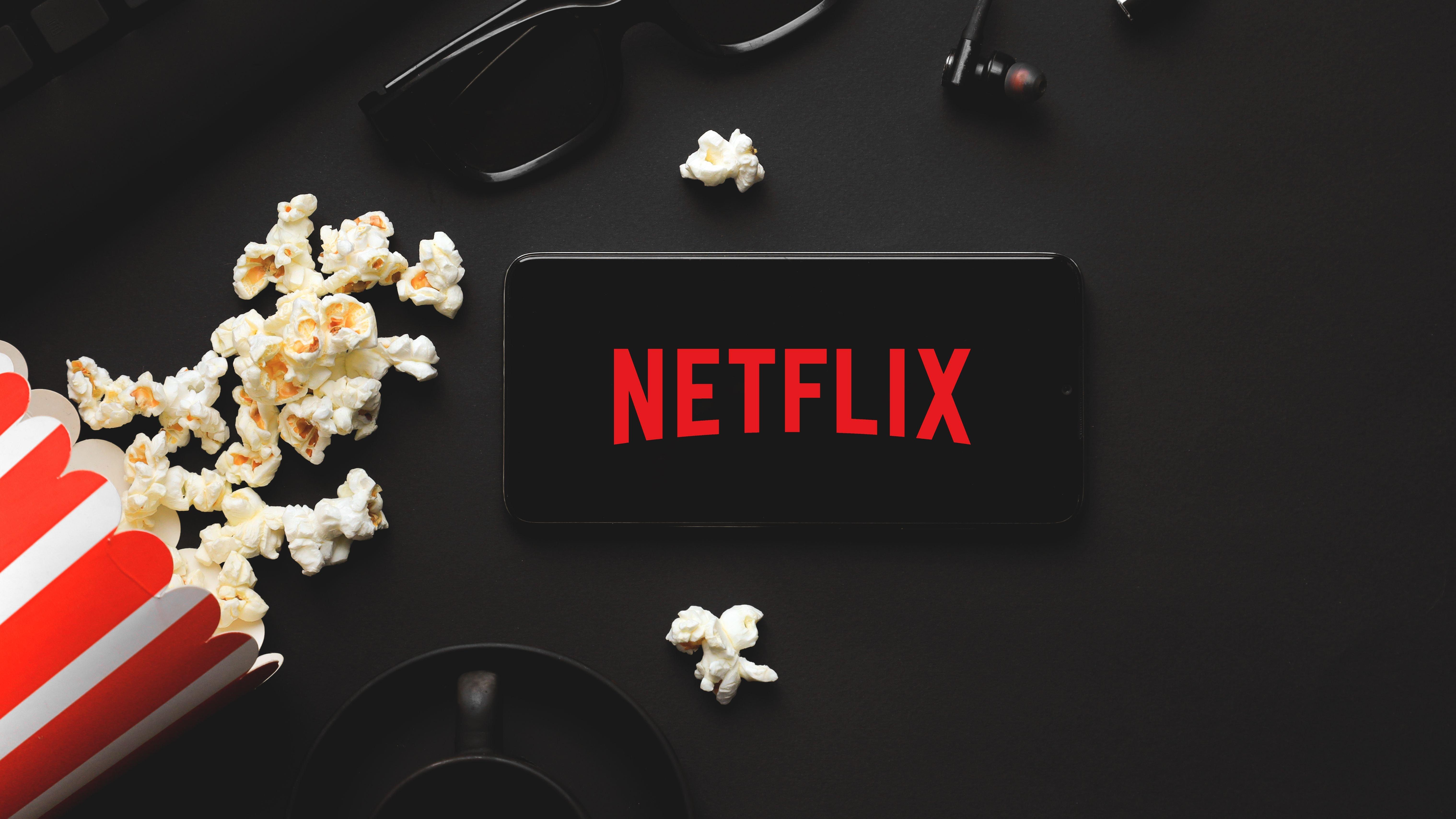 Generic picture of a spilled popcorn cup and Netflix home screen 
