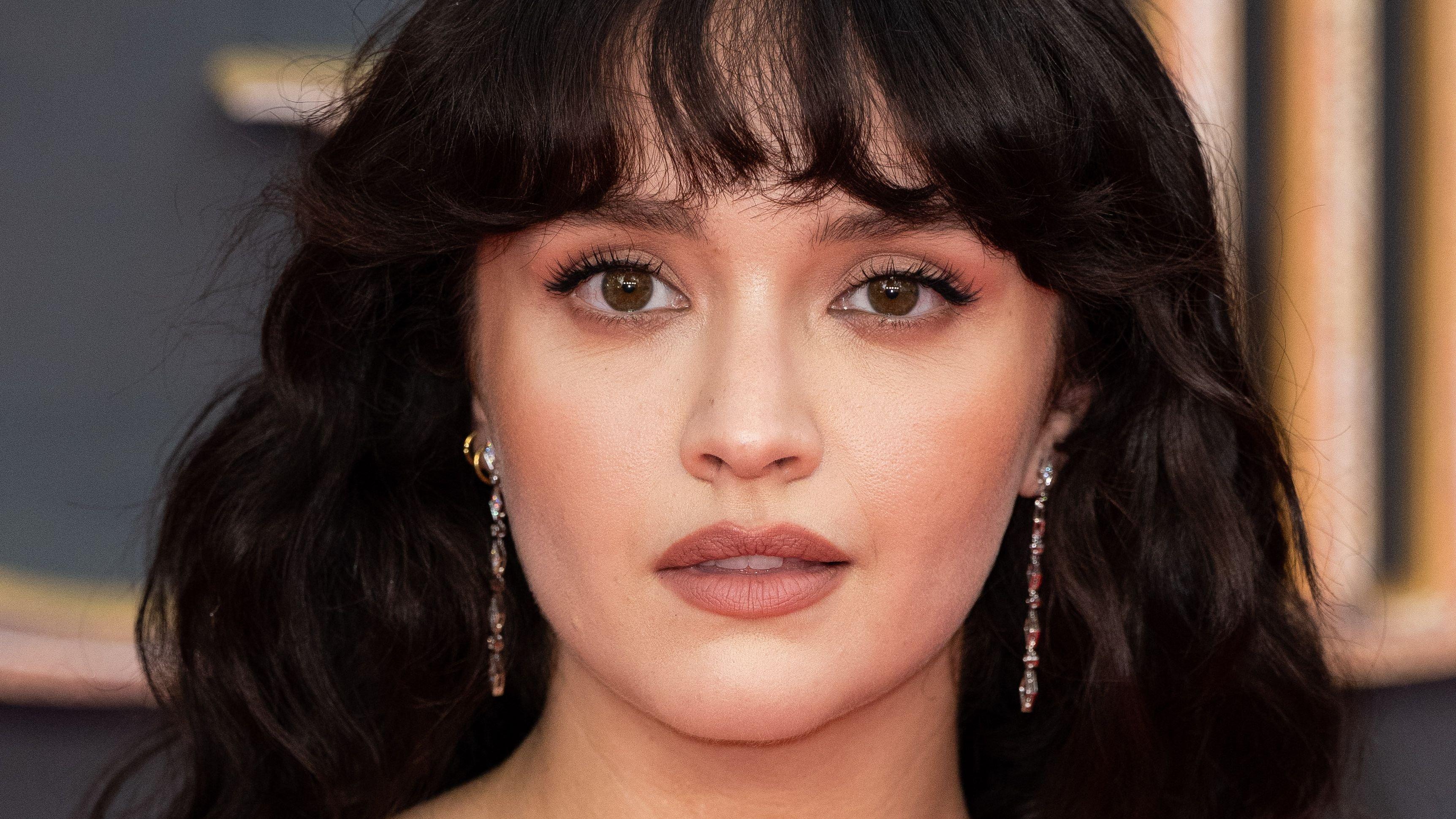 Olivia Cooke with wavy hair and bangs on the red carpet.
