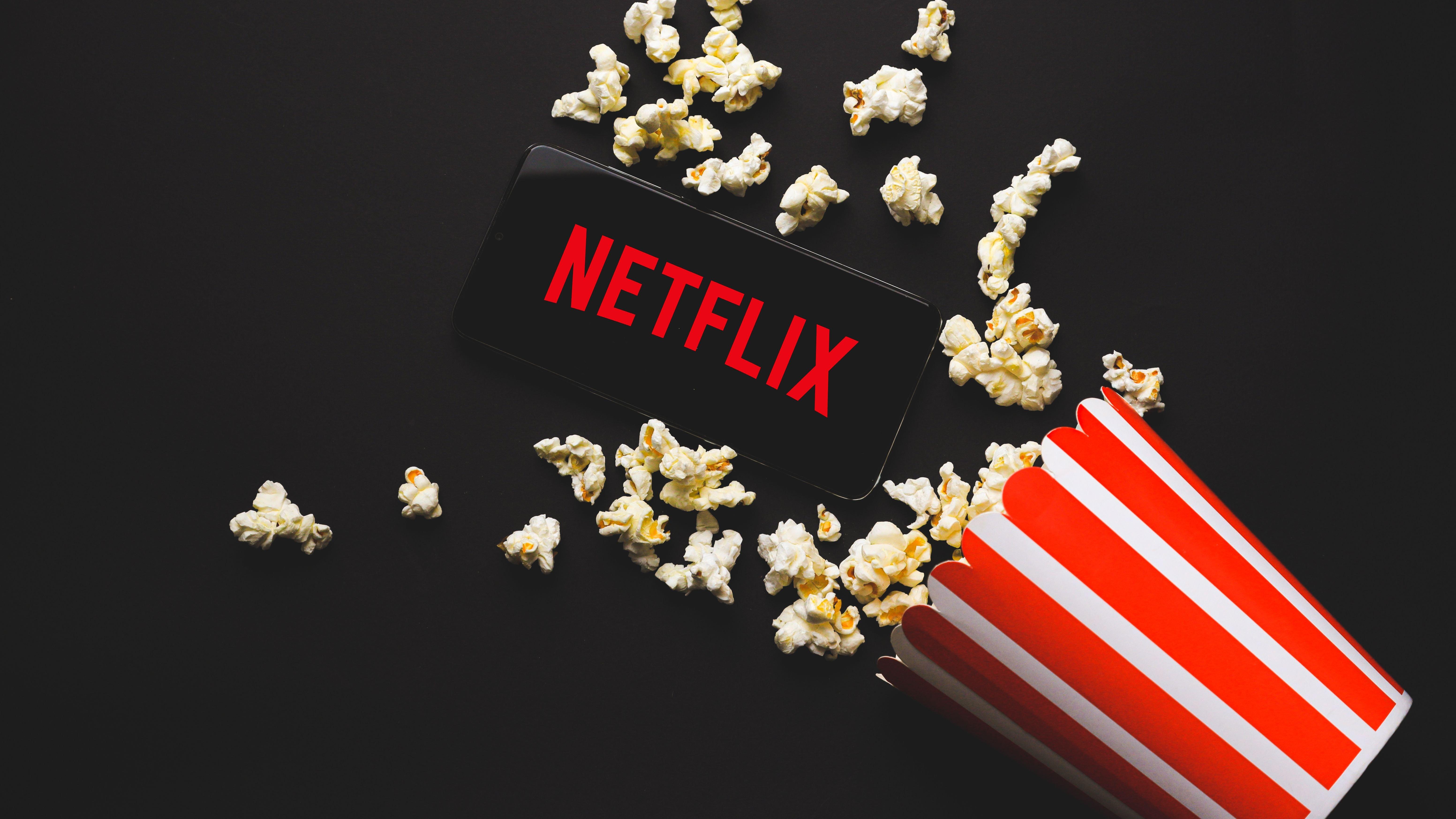 Netflix logo and a striped red & white popcorn cup with popcor flying out.