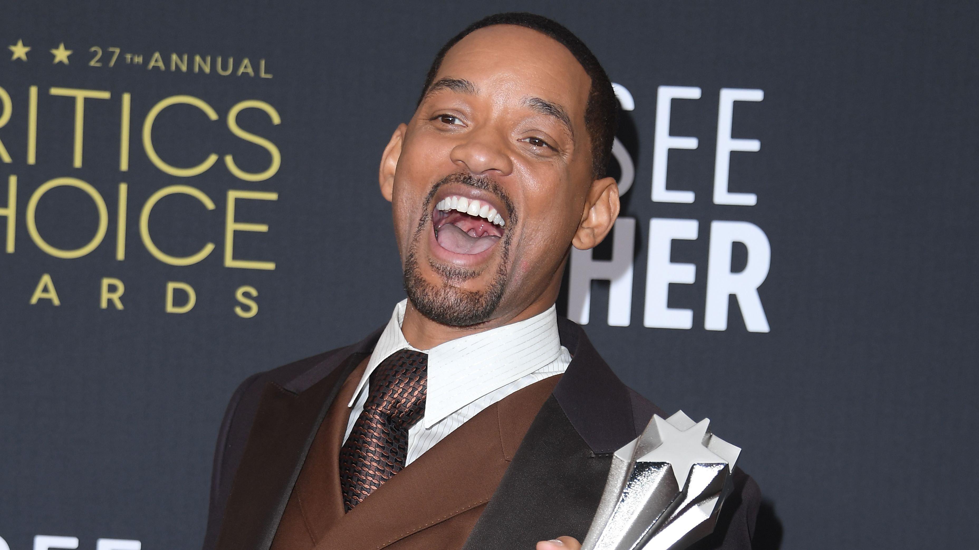 Will Smith holds Critics Choice Award with brown vest and blue suit