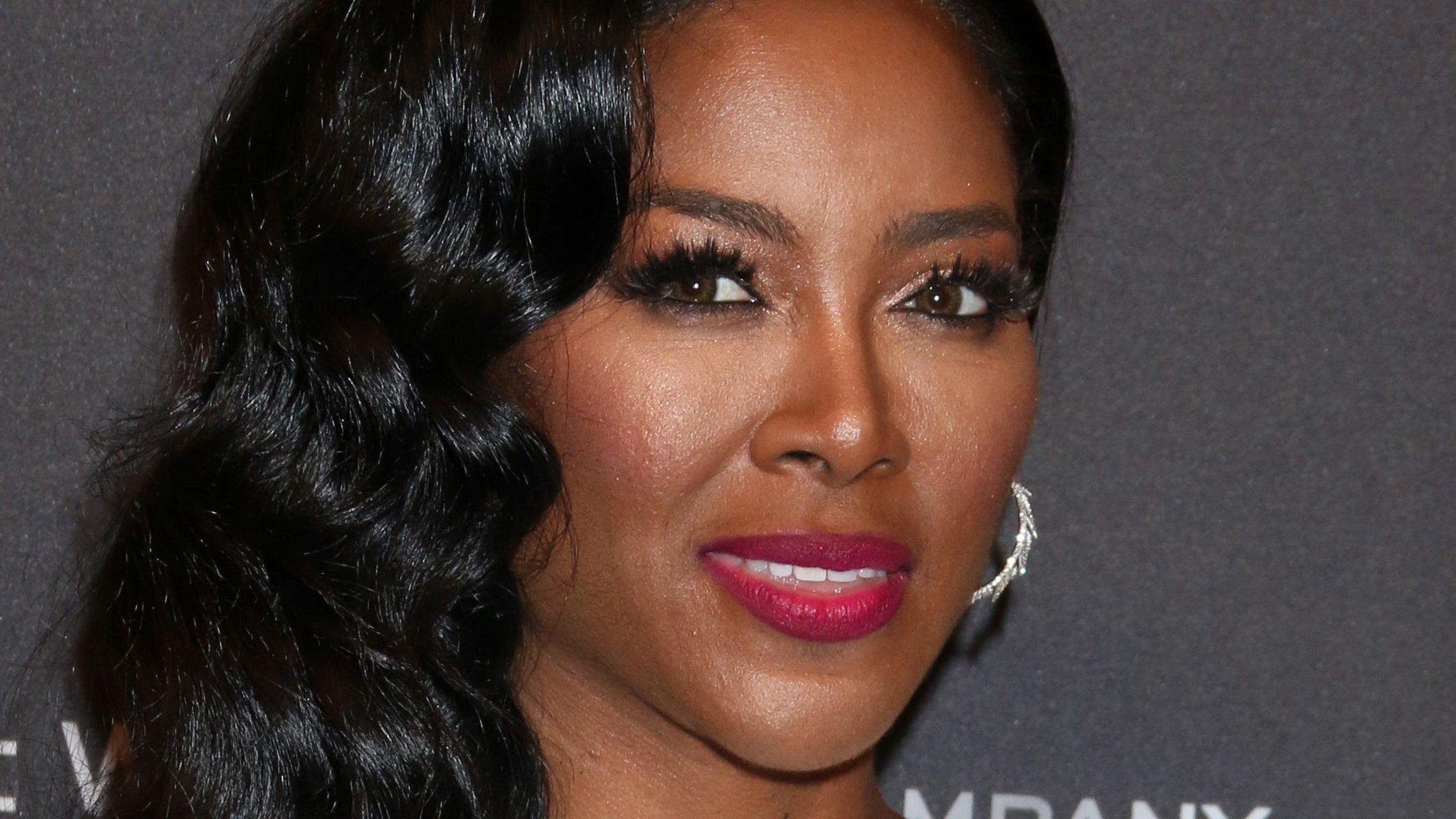 Kenya Moore with curled hair and pink lipstick