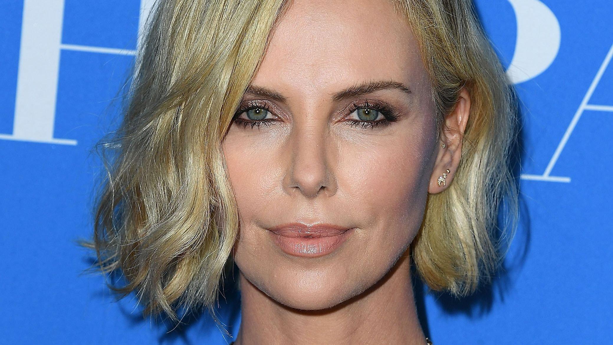 Charlize Theron with short blonde hair and smokey eye makeup.