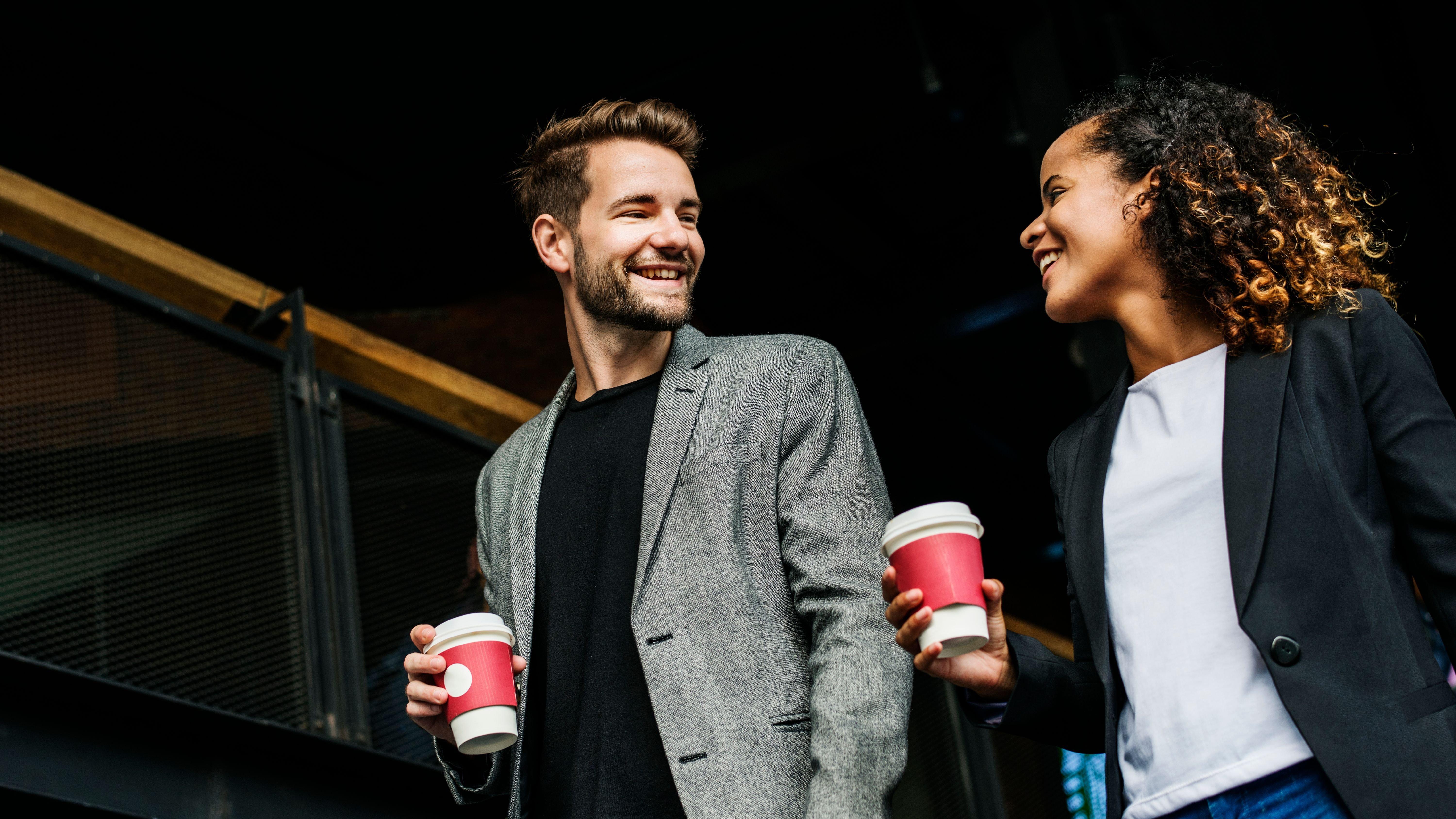 A man and a woman smiling and drinking coffee 