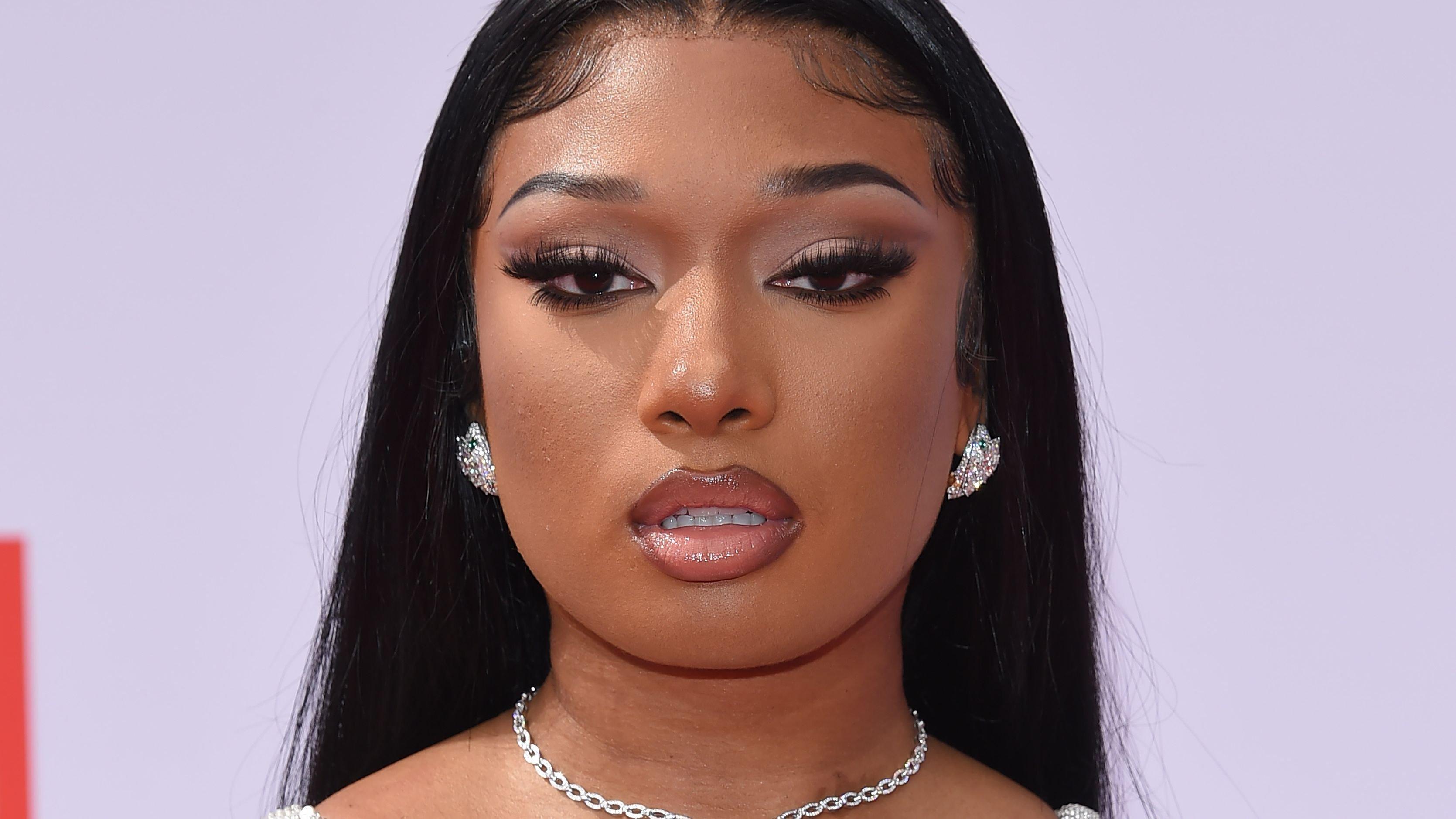 Megan Thee Stallion rocks slicked-back hair,  bedazzled strappy dress, diamond earrings, and necklace at an event.