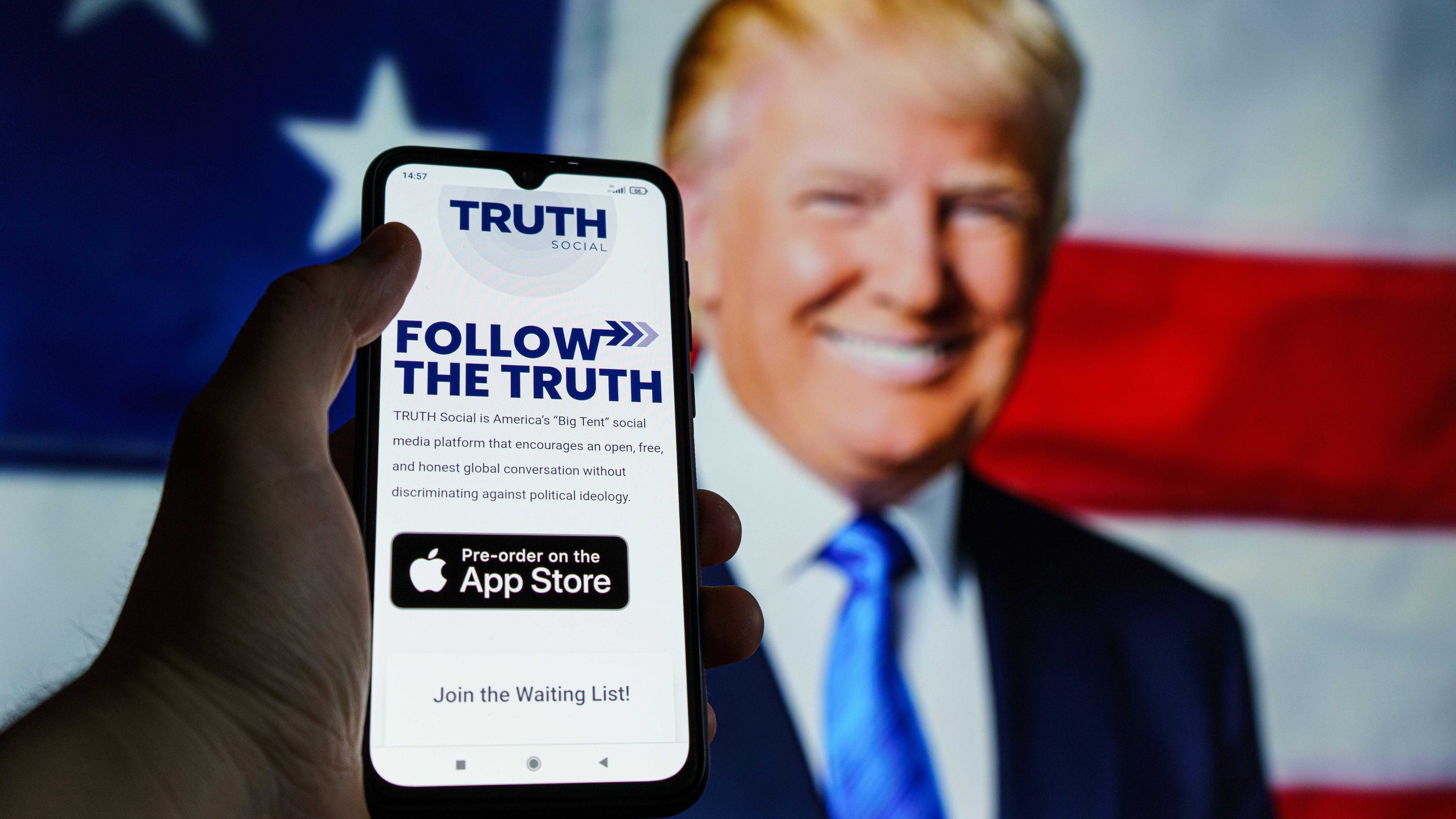 Truth Social app seen on smartphone in front of former President Donald Trump's face